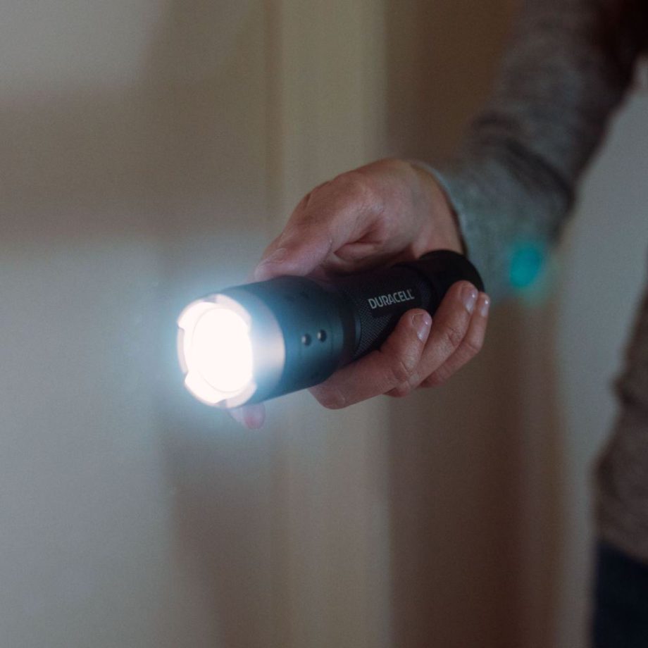 Mann hält Taschenlampe in dunkler Wohnung