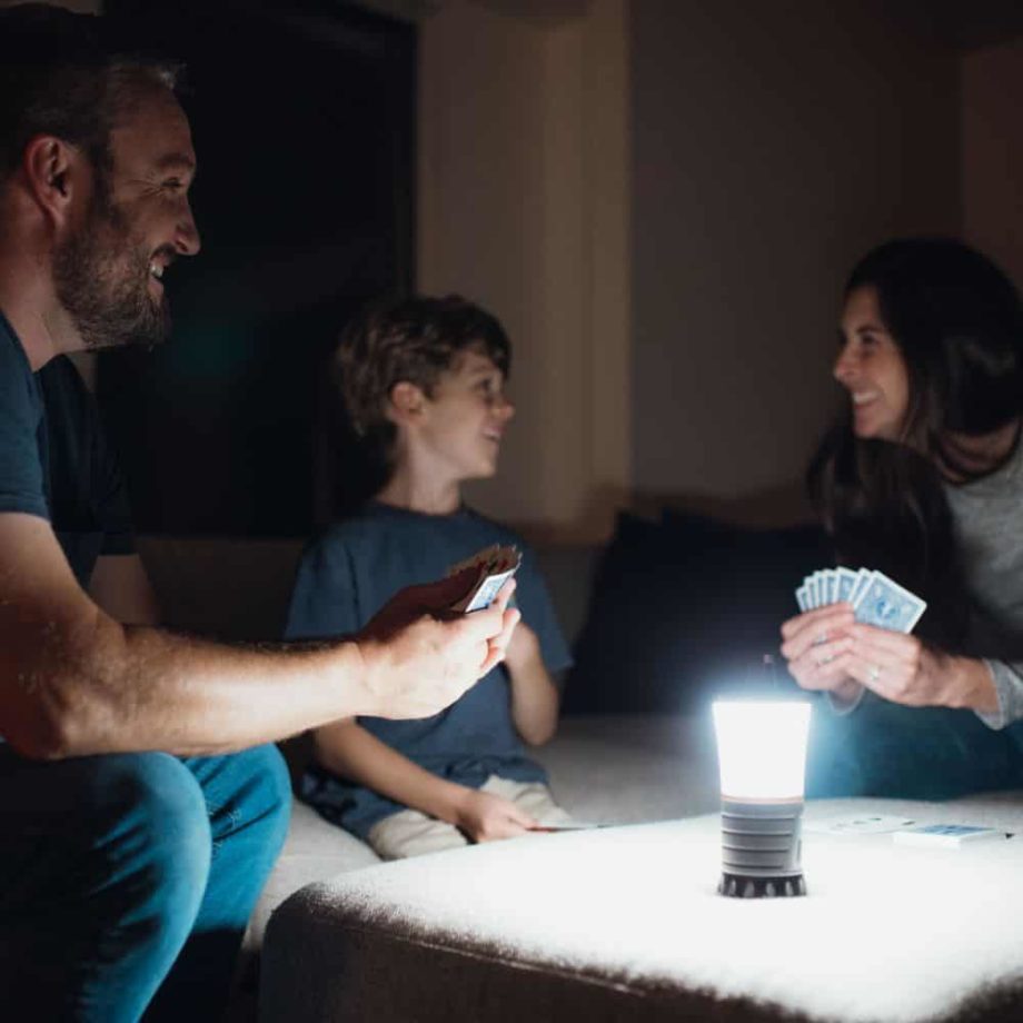 Familie spielt Karten im Dunkeln mit Laterne